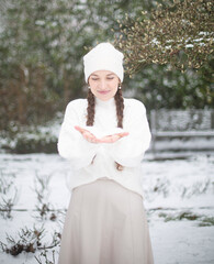 Cute young woman with white skin and long pigtails in winter park with snow