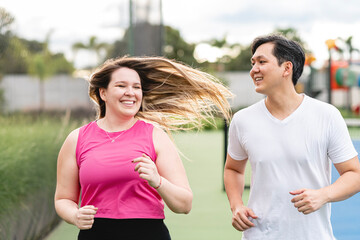 pareja muy feliz sonriendo y mirándose mientras corren en una cancha de tenis en exterior