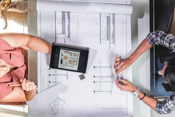 vista superior de dos mujeres arquitectos revisando planos de construcción 