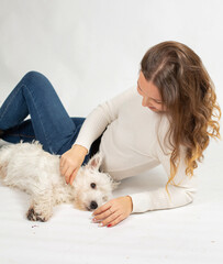 Attractive young european woman in warm white jumper isolated on white pet the dog