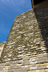 Seaside brick wall where the salty air has made the bricks crumble, leacing the mortar standing. Sunlight, day