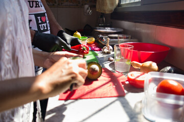 Pareja de enamorados preparando una comida colorida y fresca.  Luz natural de ventana ilumina la mesada de cocina mientras cocinan juntos. Pareja latina.