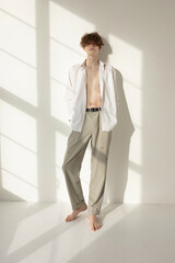 Barefoot attractive young european man with window shadow on wall
