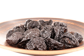 Several organic sweet prunes on a clay dish, macro, isolated on white.