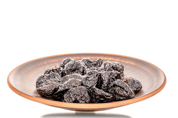 Several organic sweet prunes on a clay dish, macro, isolated on white.