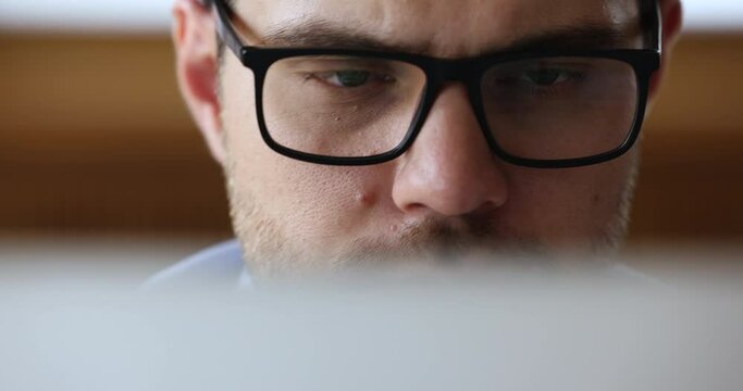 Close up view serious businessman in glasses sit in front of computer working looks at device screen. Workflow process use modern tech, eyesight check up, store ad of eyeglasses, lenses, frame concept