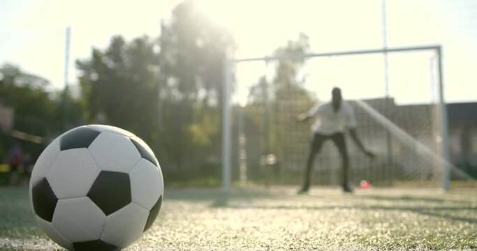 Closeup of ball on the field while man standing at soccer net