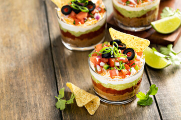 Seven layer dip in individual cups, mexican appetizer - obrazy, fototapety, plakaty