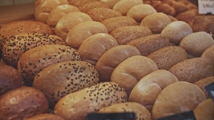 Rows of Warm Freshly Baked Bread Rolls on Display in Bakery Stand at Local Grocery Store	