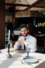 A young bearded male businessman is sitting at a table in a fine restaurant and waiting for his order. Customer service in the catering.