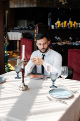 A young bearded male businessman is sitting at a table in a fine restaurant and waiting for his order. Customer service in the catering.