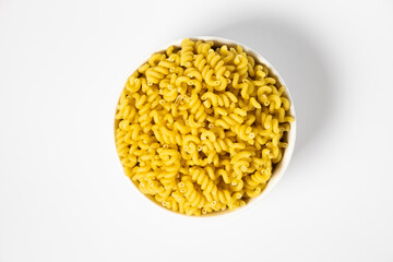 Raw Cavatappi Cellentani pasta in a plate isolated on yellow background top view