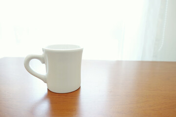 カーテンの前のテーブルに置かれたマグカップ