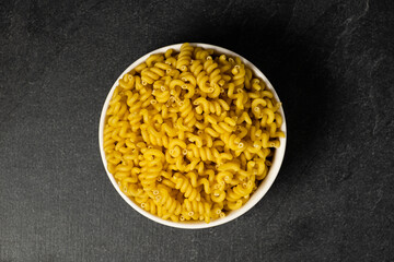 Raw Cavatappi Cellentani pasta in a plate isolated on dark background top view