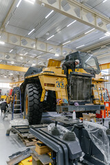 A mechanic repairs a dump truck in an industrial garage.