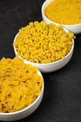 Close up of several types of dry pasta in a plate on dark background