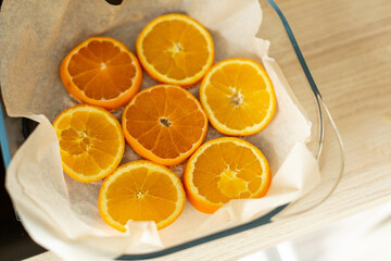 orange circles are laid out on parchment in a transparent baking dish
