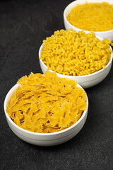 Close up of several types of dry pasta in a plate on dark background