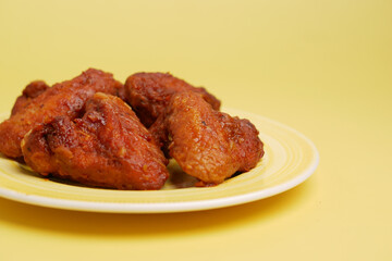 chicken wings on plate on yellow background 