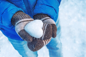 Young man holds a heart made of snow. Valentine day concept.	