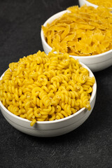 Close up of several types of dry pasta in a plate on dark background