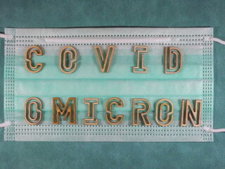 The word covid variant omicron in wooden letters on the face mask. High quality photo