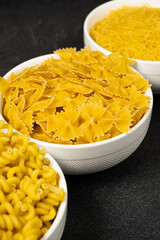 Close up of several types of dry pasta in a plate on dark background