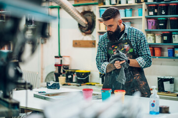 Male worker mixing colors for screen printing in a workshop