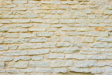 Fragment of ancient medieval fortress wall made of limestone. Vintage background. Natural old stone. Pattern in medieval style. Elements of medieval architecture. Selective focus.