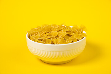 Raw Cavatappi Cellentani pasta in a plate isolated on yellow background top view