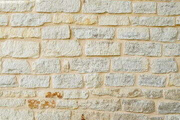 Fragment of ancient medieval fortress wall made of limestone. Vintage background. Natural old stone. Pattern in medieval style. Elements of medieval architecture. Selective focus.