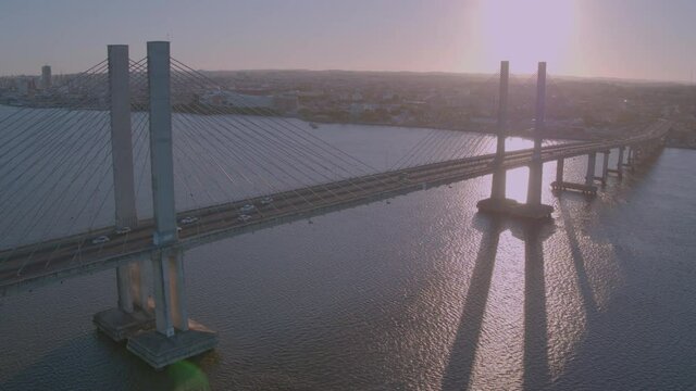 aerial view approaching the Jo&atilde;o Alves bridge on the Sergipe river in the city of aracaju with downward motion as cars pass on the bridge and the sun sets in the background