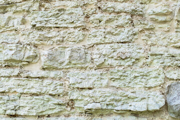 Fragment of ancient medieval fortress wall made of limestone. Vintage background. Natural old stone. Pattern in medieval style. Elements of medieval architecture. Selective focus.