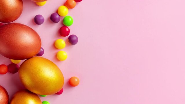 Golden Easter eggs and candies on a pink background. Happy spring holiday.