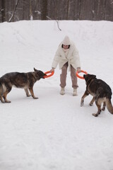 a girl in white hugs a dog against the background of snow and forest