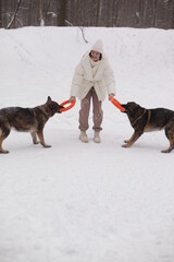 a girl in white hugs a dog against the background of snow and forest