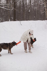 a girl in a white jacket playing with dogs