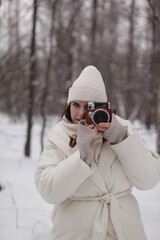 Fototapeta na wymiar a girl with a camera on a winter walk in the woods