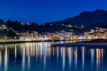 Fototapeta na wymiar Entrance to the port of Ribadesella, with Santa Marina beach in the background, on a starry night.