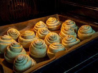 Buns on a baking tray are baked in the oven. The concept of cooking at home, delicious baked goods.