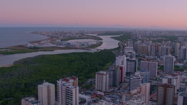 aerial view of Sergipe river with Godofredo Diniz bridge and RioMar Shopping Aracaju in the background at sunset and buildings in the foreground with avenue and cars passing by below