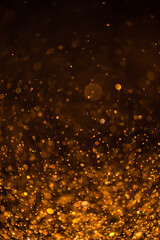 gold sequins fall on a black background. holiday, shine. texture with bokeh