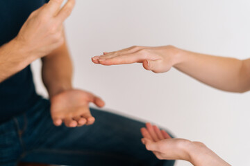 Close-up hands of unrecognizable young man and woman playing rock scissors paper game on white isolated background. Concept of resolving conflicts in a peaceful and ecological way.