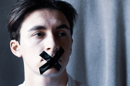 Attractive young man with mouth sealed for censorship with black tape to prevent him from speaking. International Human Right day. World Press freedom day. World Day Against Cyber Censorship