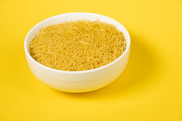 pasta for soup in a plate on yellow background