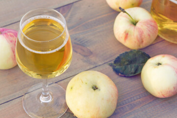 A glass of apple wine,cider, juice . Ripe summer apples are lying nearby