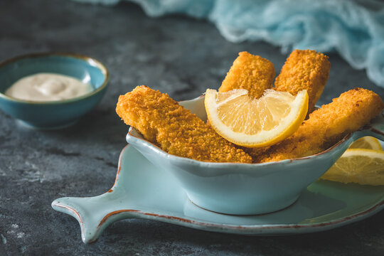 Fish fingers with lemon and sour cream on a blue background