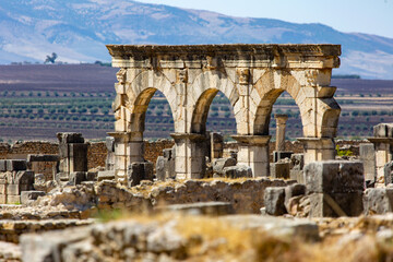 The majestic stone archways of Volubilis against the backdrop of the Atlas Mountains of Morocco