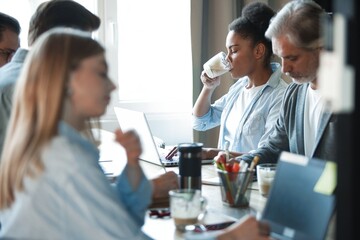 Office life. Diverse group of young businesspeople having a meeting together around a table in a modern office