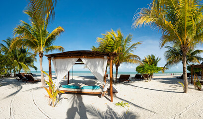 Fototapeta na wymiar Panoramic view of a beach with gazebo, lounge chairs and tropical palms on the white sand, in Holbox island in Mexico